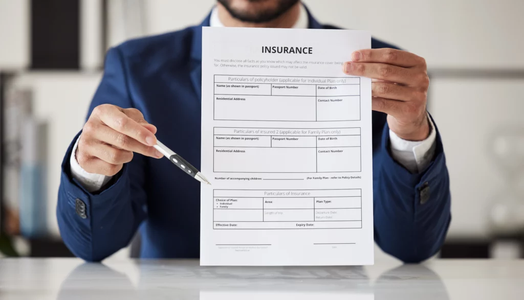 Person in a suit pointing to an insurance claim form with a pen, illustrating a quick settlement offer from an insurance company after an accident.